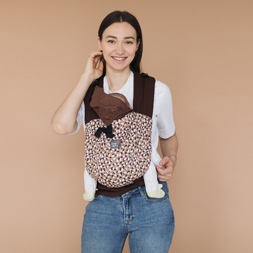A mother wearing a patterned Mei Tai carrier with her baby in an ergonomic position.